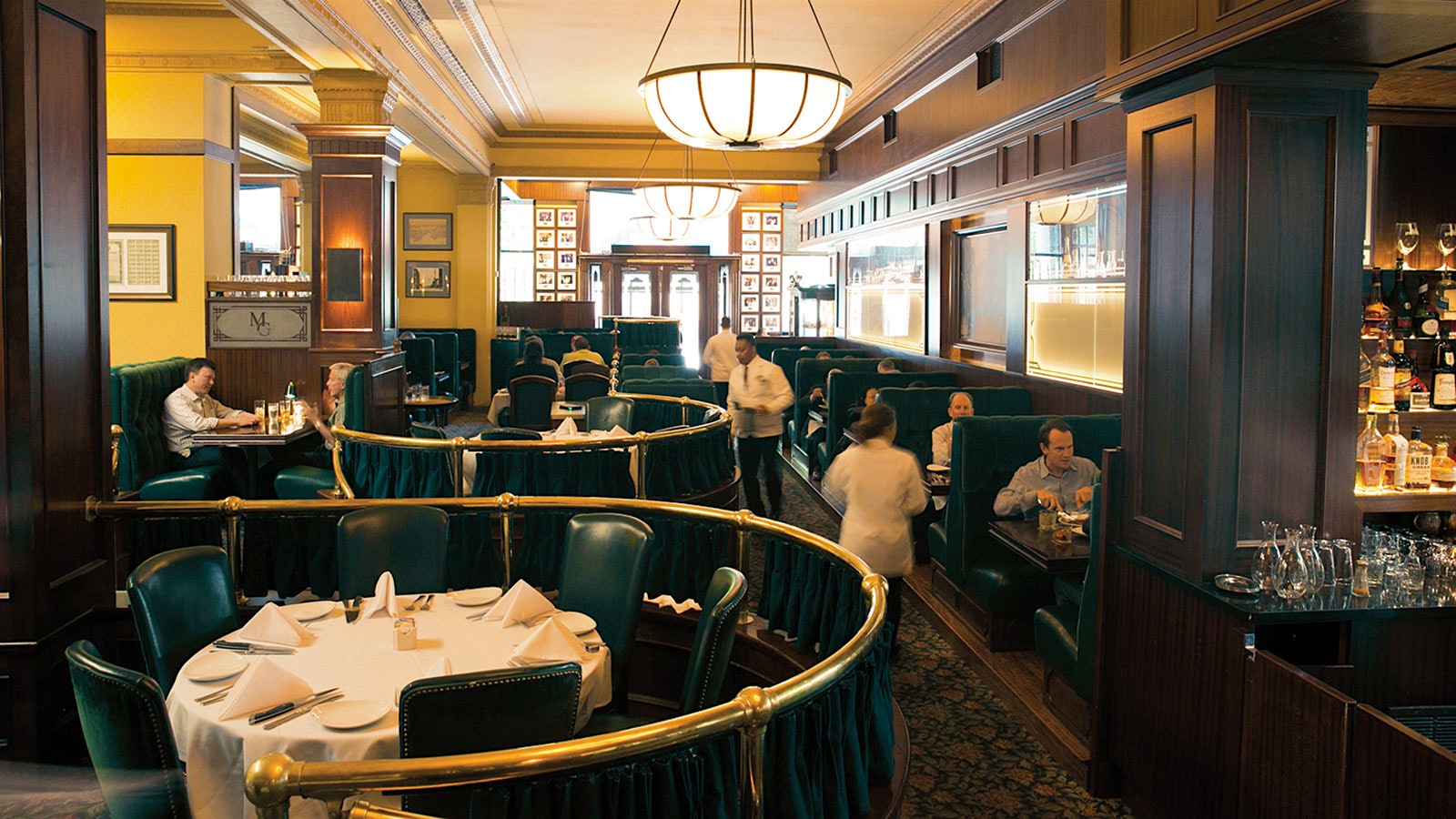 People in the Metroplitan Grill dining room, with leather banquettes and brass and wood furnishings
